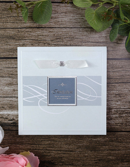 Closed view of 7006 Light Blue Accent Silver Invitation, showcasing shimmering pearlescent cardstock in shades of blue, a square window cutout, and a white ribbon for a luxurious and elegant look