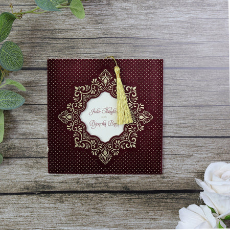 Close-up of Square Red Velvet Wedding Invitation SC 5596 with gold foil details and tassel, featuring an ornate cut-out window.