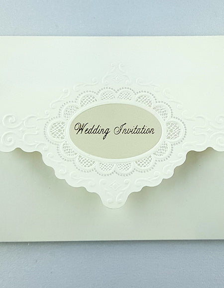 Close-up of embossed floral wreath on off-white wedding invitation with gold foil text