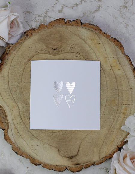 Front view of 5068 Small Square Wedding Invitation, showcasing four silver letterpress foiled hearts on a white background, priced at 50p each for affordable elegance