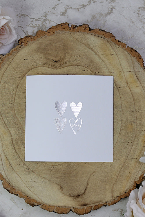Load image into Gallery viewer, Front view of 5068 Small Square Wedding Invitation, showcasing four silver letterpress foiled hearts on a white background, priced at 50p each for affordable elegance
