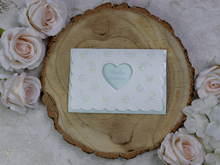 Front view of 7121 White Pearlescent Shimmer Invitation, showcasing a heart-shaped cutout and small bouquets of green and pink embossed flowers, creating a romantic and elegant design