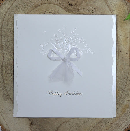 Flat-lay of BW21 folded wedding invitation highlighting wavy die-cut edges and elegant hand-tied bow.