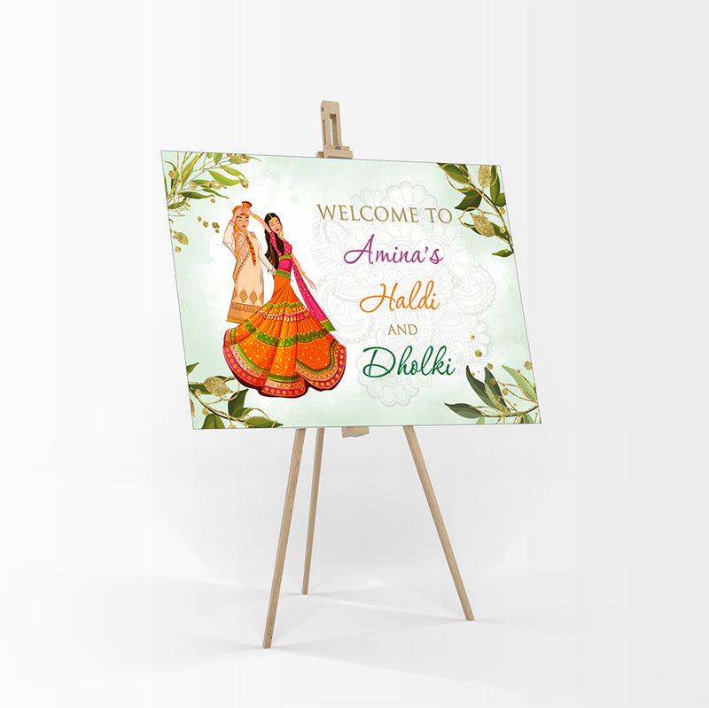welcome board for haldi ceremony with green leaves and caricaure of Indian bride & groom
